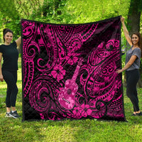 Large quilt draped on grass: pink and dark Polynesian ukulele and flower swirl pattern.