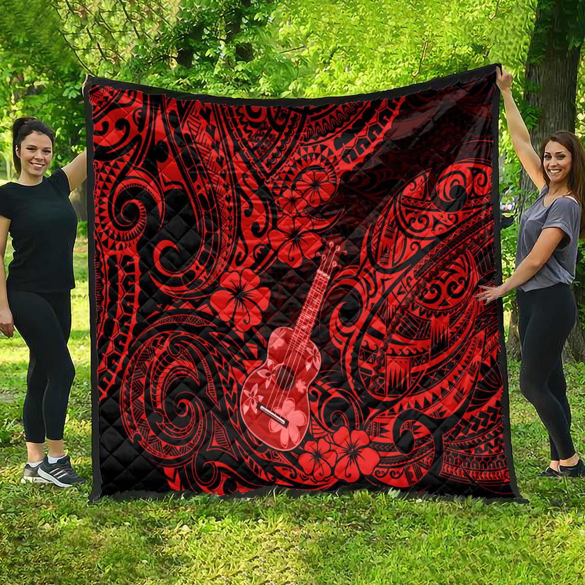 Red and black Polynesian quilt draped outdoors, featuring ukulele and flower motifs