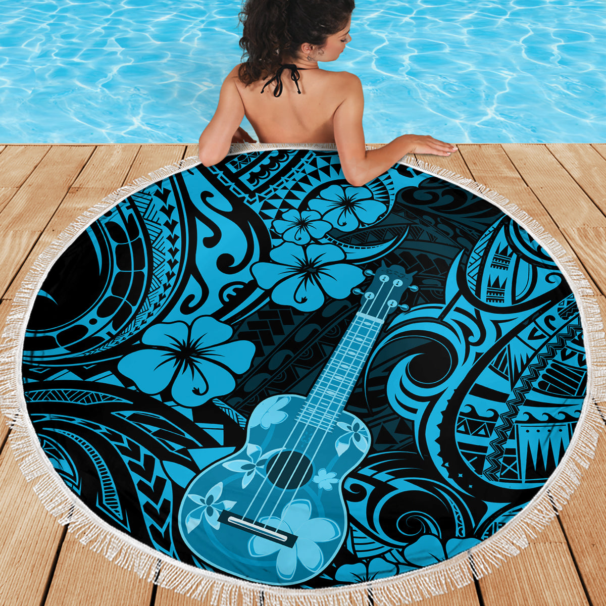 Round beach blanket on pool deck, blue polynesian ukulele print with fringed edge