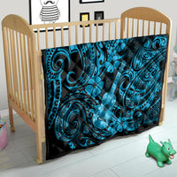 Blue Polynesian ukulele quilt blanket on baby bed, black border with turquoise swirl motifs