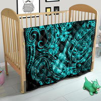 Turquoise Polynesian pattern quilt on a crib mattress with ukulele and hibiscus motifs