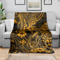 Gold and black Polynesian fish hook throw blanket with floral and tiki motifs, draped