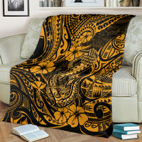 Gold and black Polynesian fish hook throw blanket with floral motifs, draped on couch