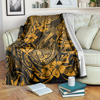 Gold and black Polynesian fish hook throw blanket with floral motifs, draped over sofa