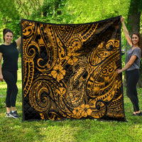 Gold-and-black Polynesian fish hook quilt with bold swirling motifs, held outdoors