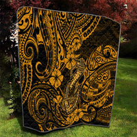 Gold-and-black Polynesian fish hook quilt with ornate swirling pattern, draped on grass