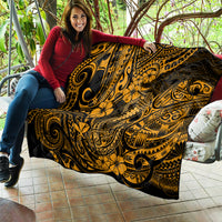 Gold-and-black Polynesian fish hook quilt with swirling floral design, draped on couch