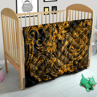 Gold-and-black Polynesian fish hook quilt with swirling floral pattern, on a baby bed