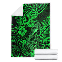 Green Polynesian fish hook blanket shown with folded stacks and tribal print