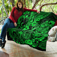 Green Polynesian fish-hook quilt with clover and swirl motifs, draped on sofa