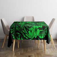 Green Polynesian tablecloth with ornate swirls, palm and hook motifs, square over table