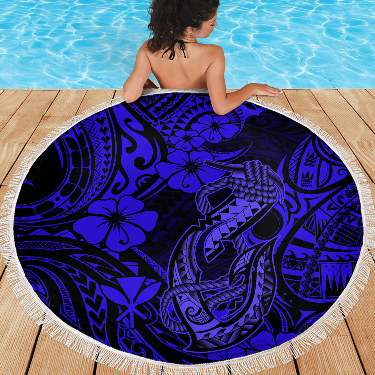 Round navy Polynesian fish hook beach blanket with fringe edge, draped on deck