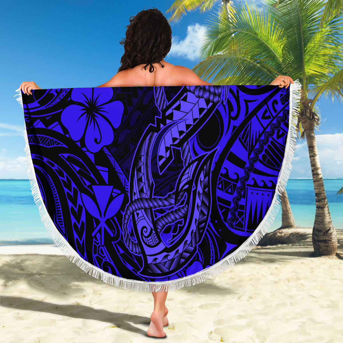Round navy Polynesian fish hook beach blanket with fringe edge, held open as wrap
