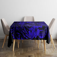 Navy blue tablecloth with Polynesian fish hook and floral motifs, covering square table.