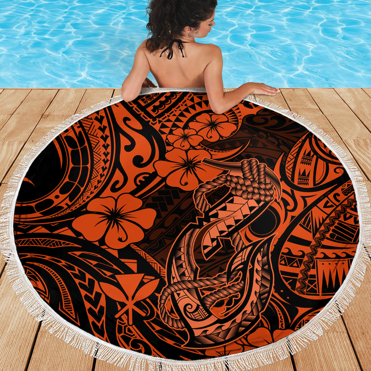 Orange circular beach blanket with black Polynesian design and white tassel fringe border