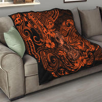 Orange and black Polynesian-pattern quilt folded on a sofa, patterned with spirals