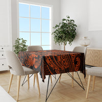 Orange and black Polynesian tablecloth covering dining table with repeating decorative motifs