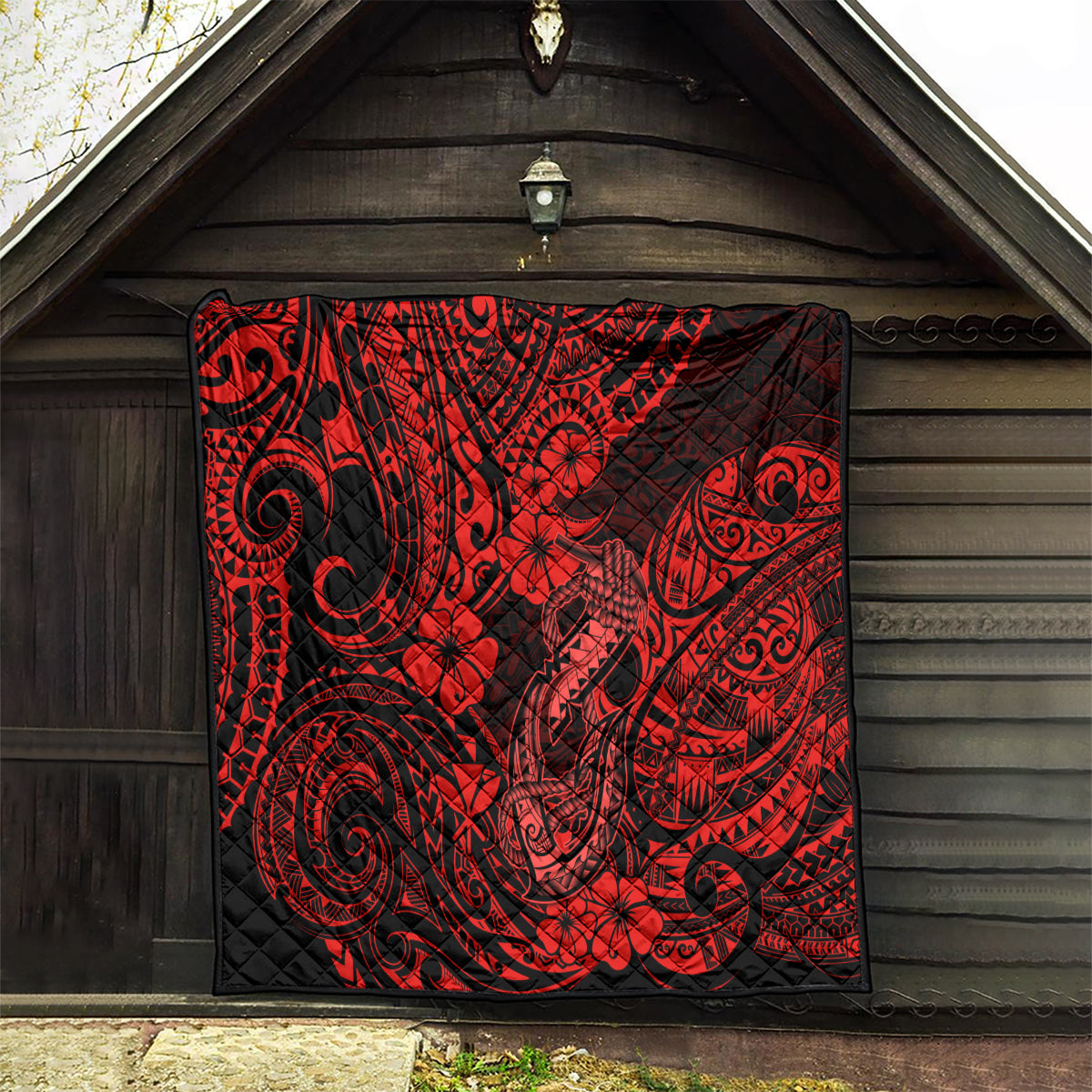 Red and black quilt blanket with hibiscus flowers, tribal swirls, and fish hook motifs