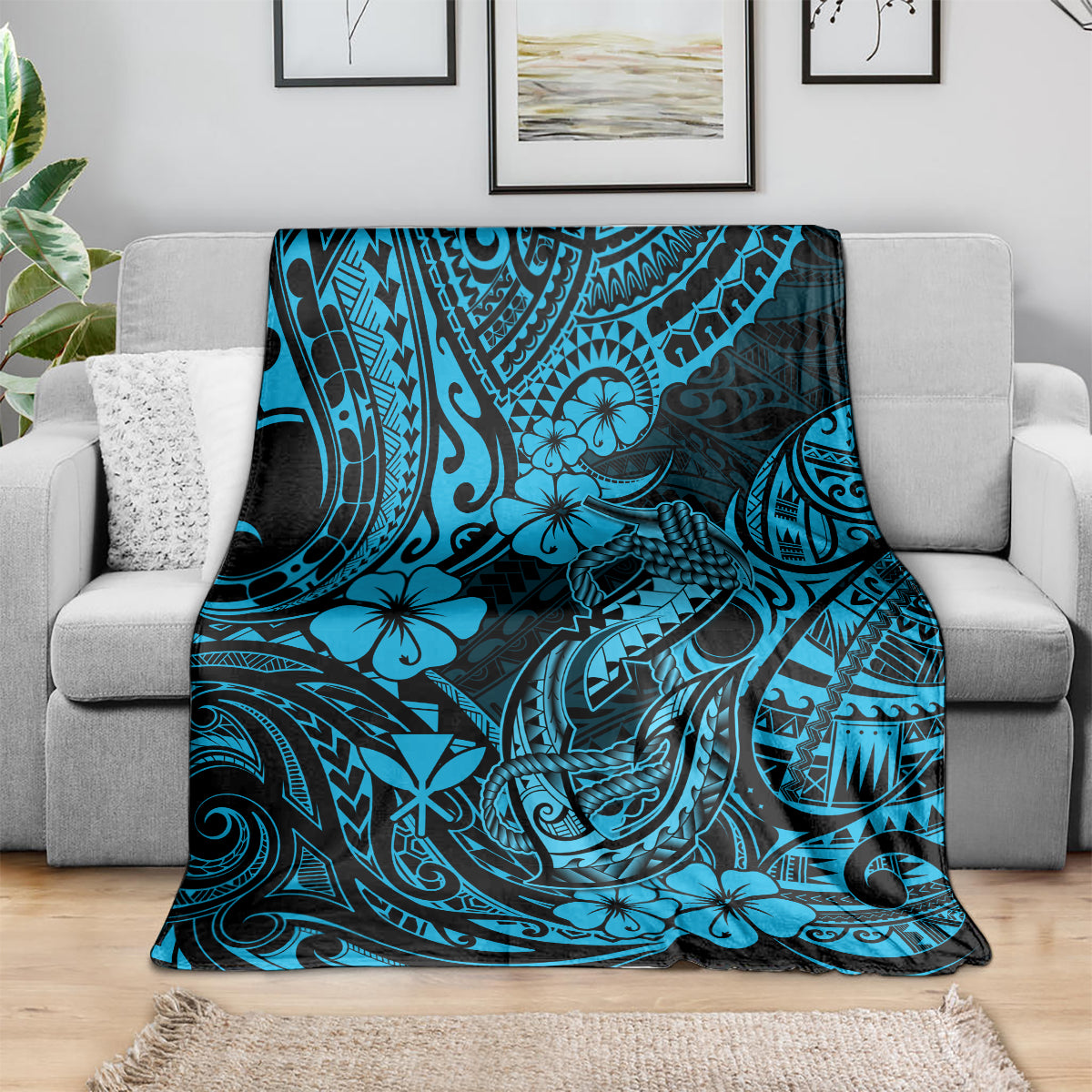Blue tribal-style throw blanket draped over a gray sofa, hibiscus and fishhook print