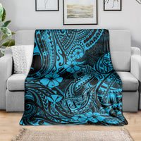 Blue tribal-style throw blanket draped over a gray sofa, hibiscus and fishhook print