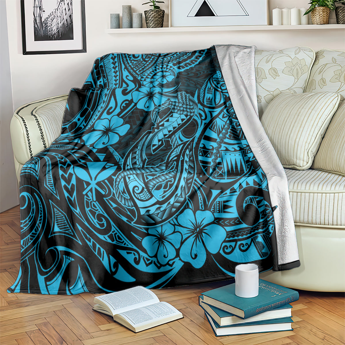 Blue patterned throw blanket draped on a sofa back with hibiscus and fishhook motifs