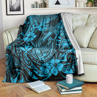 Blue patterned throw blanket draped on a sofa back with hibiscus and fishhook motifs