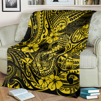 Yellow and dark patterned hibiscus and fishhook throw blanket over a couch