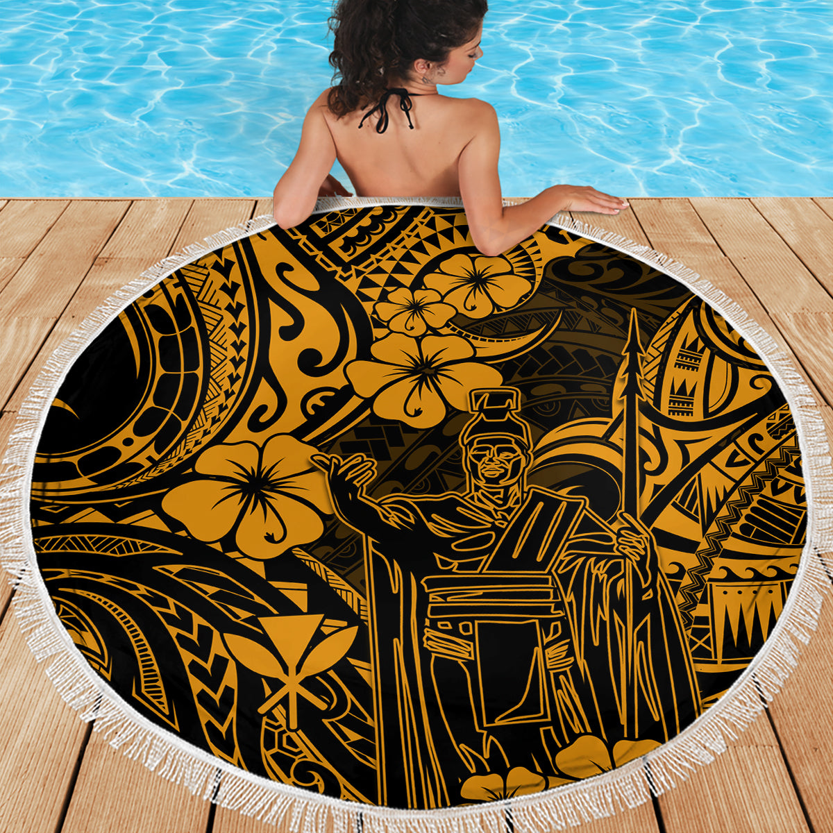 Round beach blanket with white fringe, gold and black Polynesian King Kamehameha pattern, held