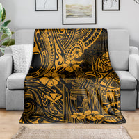 Gold and dark Polynesian pattern throw blanket draped over a sofa, with hibiscus-style flowers