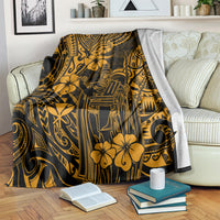 Gold and dark Polynesian pattern blanket draped on a bed with floral motifs and face emblem