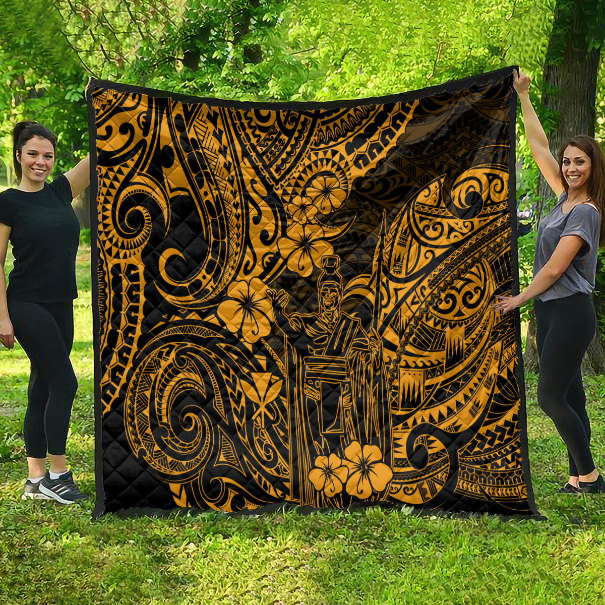 Gold and black Polynesian-pattern quilt draped outdoors, showing ornate swirls and flowers