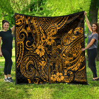 Gold and black Polynesian-pattern quilt draped outdoors, showing ornate swirls and flowers