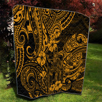 Gold Polynesian-pattern quilt with black backing, featuring tribal faces, swirls, and hibiscus-like blooms