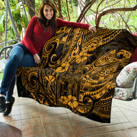 Gold Polynesian-pattern quilt laid over sofa, black background with ornate swirls and flowers