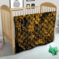 Gold Polynesian-pattern quilt on a baby bed, black and gold swirls with flower motifs