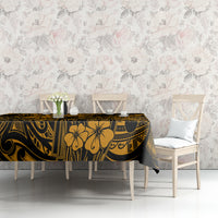 Gold and black patterned tablecloth on a table with floral lattice-style design across fabric.