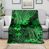 Green Polynesian pattern throw blanket draped over a gray sofa.