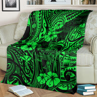 Green Polynesian pattern blanket spread over an upholstered sofa and pillows.