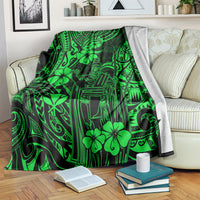 Green Polynesian pattern blanket folded over a couch with books on the floor.