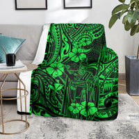 Green Polynesian pattern blanket on a gray chair seat with side tables.