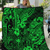 Green Polynesian pattern quilt with black background, shown folded outdoors