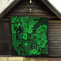 Green Polynesian pattern quilt displayed on a wooden wall outdoors