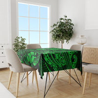 Green polynesian tablecloth covering table with matching border and leaf-and-arch pattern