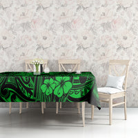 Green polynesian tablecloth on table, patterned with geometric lines and hibiscus-style flowers