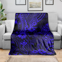 Navy blue patterned blanket with floral and tiki face motifs, spread across a couch