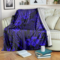 Navy blue blanket with hibiscus and tribal glyph motifs, draped over couch arm