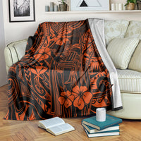 Orange and black Polynesian pattern blanket with king figure and hibiscus flowers, folded on sofa