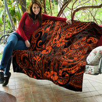 Orange and black Polynesian quilt on couch, featuring swirling tiki patterns and flowers