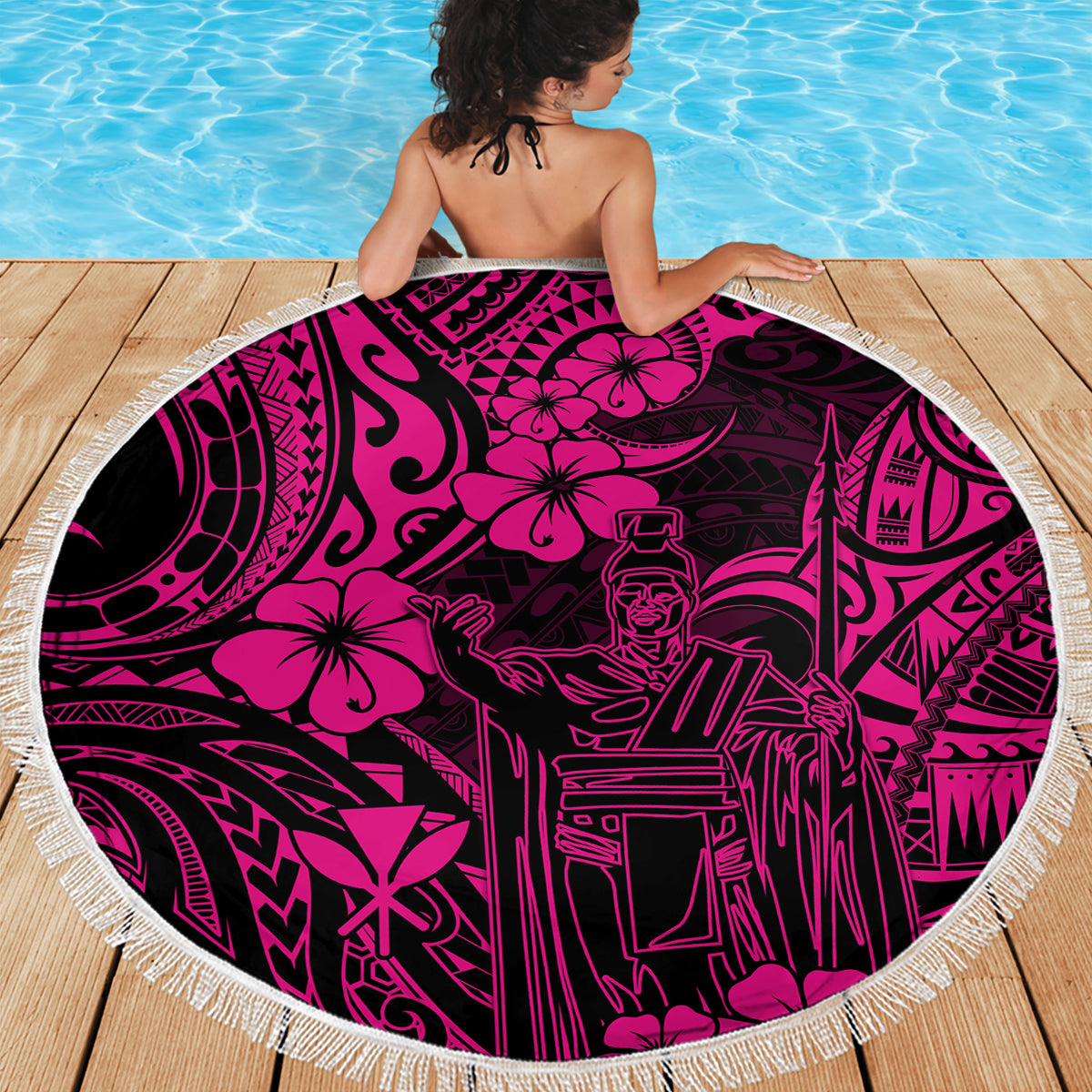 Pink circular beach blanket with white fringe and dark Polynesian figures pattern