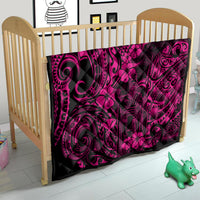 Pink Polynesian quilt in a baby crib with dark fabric and swirl floral pattern